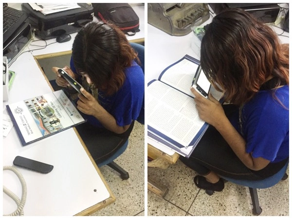 a client of trinidad and tobago blind welfare association viewing the 100 years celebration magazine using zoomax m5 hd plus distance viewing mode reading stand closed