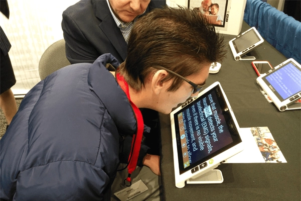 visitor trying text to speech function of zoomax snow 10 pro video magnifier at atia 2018 conference