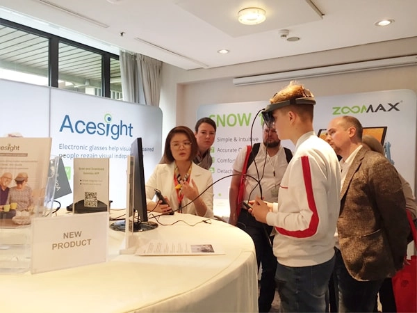 zoomax staff giving the visitor a demo of wearable vision aids acesight