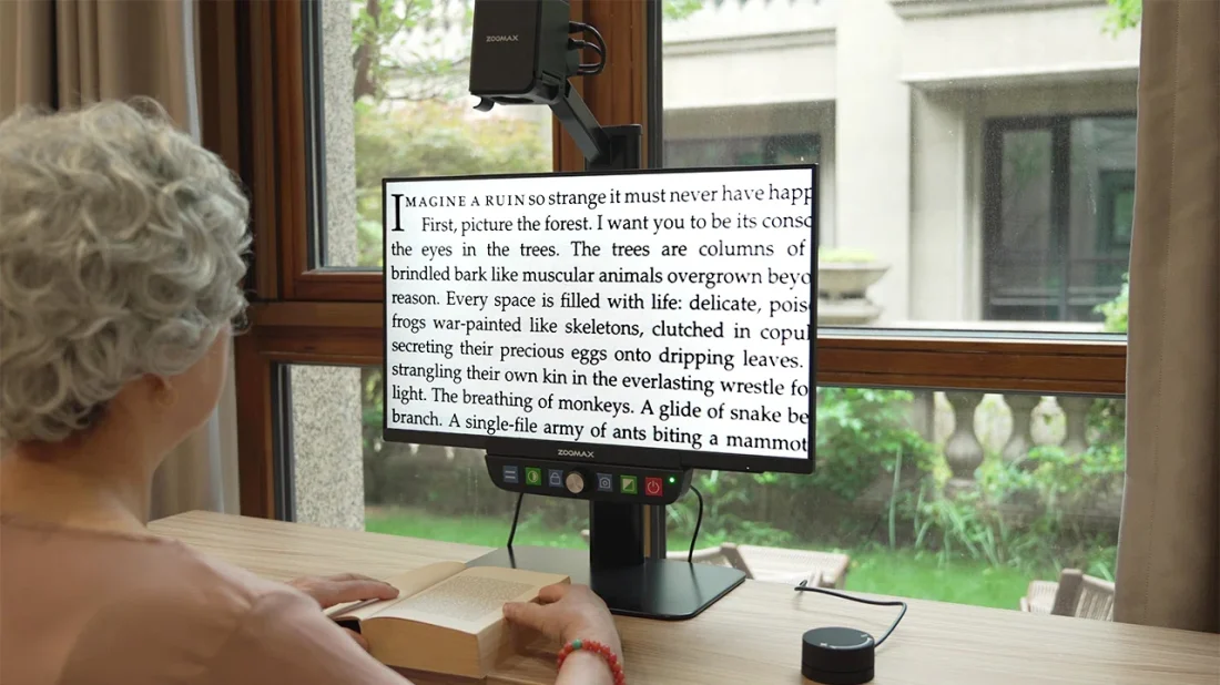 person using zoomax luna eye low vision electronic magnifier to read a novel